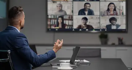 A person is sitting in front of a video conference screen.